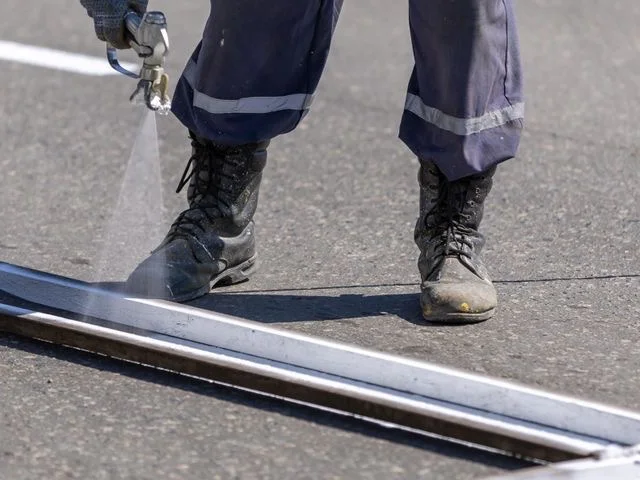Szakember útburkolati jelet fest fel spray-berendezéssel az úttestre